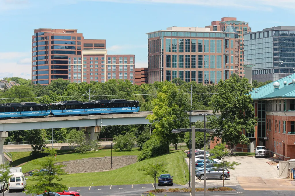 MetroLink train on an elevated track below office towers in downtown Clayton, Missouri